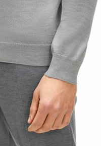 Grauer Strickpullover mit Rundhalsausschnitt und gerippten Bündchen, aus weichem, leichtem Material, zusammen mit einer passenden Hose präsentiert.
