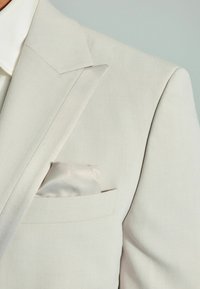 Hellgrauer Blazer mit scharfen Revers, tailliertem Schnitt und strukturiertem Stoff. Mit einem Taschentuch in zartem Satin-Finish.