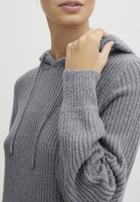 Grå ribbad hoodie med en texturerad yta, justerbara snören och en avslappnad passform. Mjuk tygkvalitet med medelvikt.