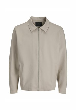 Chaqueta de un beige claro con cierre de cremallera, tela suave, cuello con solapa y dos bolsillos laterales. Diseño simple y corte relajado.