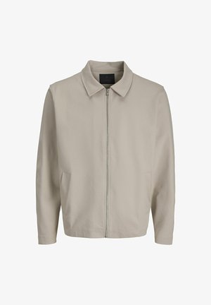 Lichtbeige jack met een rits aan de voorkant, zachte stof, een kraag en twee zijzakken. Eenvoudig ontwerp en comfortabele pasvorm.