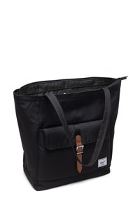 Sac en toile noir avec fermeture éclair, poche avant, accent en cuir marron, et deux sangles pour le porté épaule.
