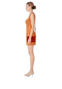 Bolso cruzado de charol rojo con un acabado brillante, que presenta una correa larga y ajustable, forma rectangular y un diseño minimalista.