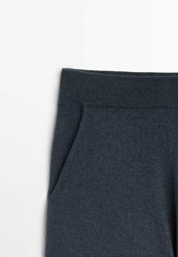 Donkergrijze gebreide broek met een geribbelde elastische tailleband en zijzak, weergegeven op een witte achtergrond.