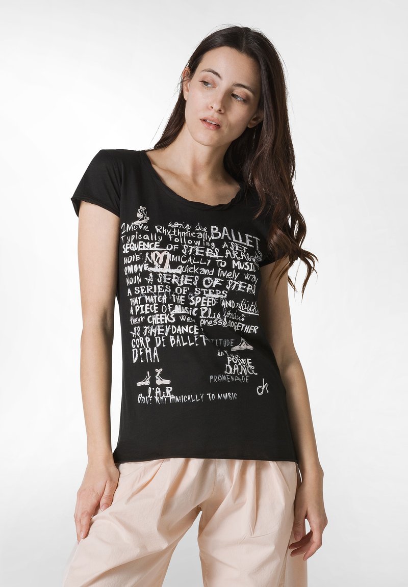Sort t-shirt med hvid tekst og ballet-inspirerede grafikker. Korte ærmer, rund hals, med forskellige danse-relaterede sætninger og illustrationer.