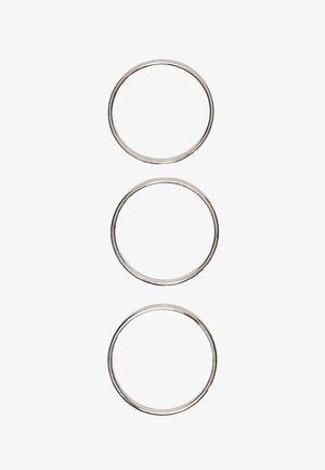 Drie identieke dunne metalen ringen verticaal uitgelijnd op een witte achtergrond.