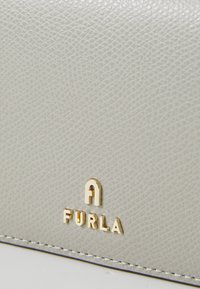 Light gray textured leather pouch featuring a gold embossed logo "FURLA" and fine stitching along the edge. Compact rectangular shape.
