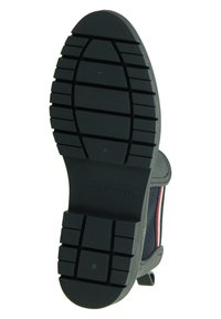 Suola di scarpa in gomma nera con grip testurizzato e scanalature profonde. Presenta il marchio "TOMMY HILFIGER" nella parte del tallone.