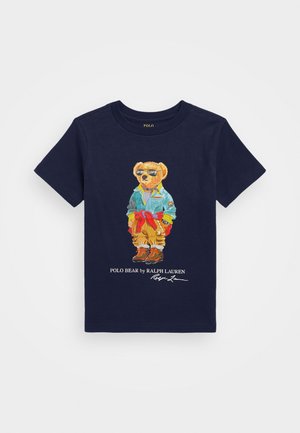 Marineblaue Baumwoll-T-Shirt mit einem Cartoon-Bären in einer Jeansjacke und stylischen Sonnenbrillen, mit einer Illustation des Bären und einem Logo darunter.
