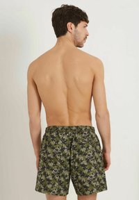 Miesten camouflageswimshortsit tummanvihreänä, harmaana ja mustana; elastinen vyötärönauha, jossa on naru; kevyttä, nopeasti kuivuvaa kangasta.