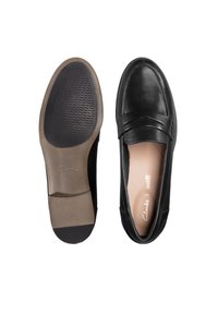 Mustat nahka loaferit, joissa on teksturoitu kumipohja. Kengässä on etuosan hihnan yksityiskohta ja pehmustettu sisäpohja.
