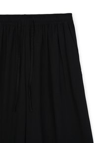 Pantaloni neri a gamba larga realizzati in tessuto morbido, con una vita elasticizzata dotata di lacci regolabili e dettagli plissettati per un volume extra.