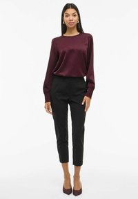 Bordeaux satin langærmet bluse parret med sorte skræddersyede cropped bukser og matchende bordeaux højhælede sko; glat tekstur og tætsiddende design.