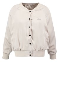 Veste bomber en satin beige clair avec un col rond, des poignets élastiqués et des boutons noirs sur le devant. Dispose de poches latérales.