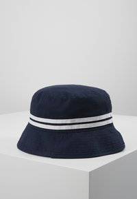 Marinblå bucket hat i bomull, med två horisontella vita ränder runt basen. Skärmen är bred och något texturerad.