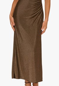 Abito lungo in maglia metallizzata marrone con arricciature in vita, texture liscia e silhouette aderente; lungo fino alla caviglia con una leggera lucentezza.