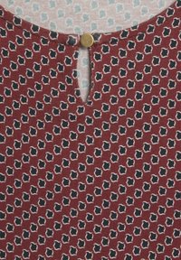 Burgunderfarbenes gemustertes Oberteil mit einem Schlüssellochausschnitt und goldenen Knopfakzenten, verziert mit kleinen marineblauen Formen, die in Creme umrandet sind.