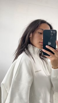Sudadera blanca con cremallera y cuello alto, puños acanalados y corte ligeramente oversize. Detalle del logo sutil en el pecho. Textura suave.