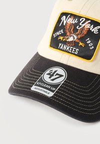 Μπεζ και μαύρο καπέλο μπέιζμπολ με κεντημένη στάμπα των New York Yankees που απεικονίζει έναν αετό και το κείμενο «Since 1903».