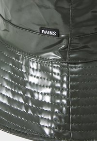 Green rain bucket hat made of glossy material with quilted texture, featuring a small black label with the brand name "RAINS."