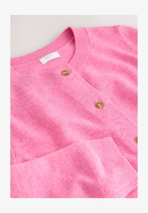 Rosa ullkofta med rund halsringning, ribbade muddar och knappar fram i en kontrasterande ljusguldfärg.