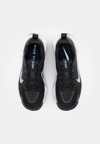 Black and white athletic shoes with a mesh upper, prominent laces, and light blue accents. Features Nike branding on the tongue and sides.