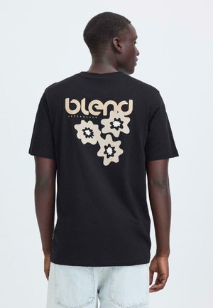 Schwarzes Baumwoll-T-Shirt mit "blend"-Logo und floraler Grafik in hellem Beige auf der Rückseite. Kurze Ärmel und lockere Passform.