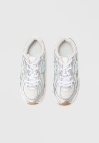 Chaussures de sport grises et blanches avec une tige en mesh, des accents argentés réfléchissants et des détails bleu clair ; elles possèdent des lacets et une semelle en caoutchouc.