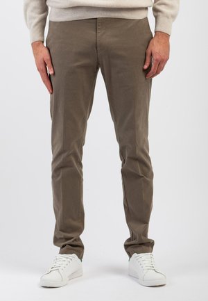 Chino color marrone chiaro in cotone, con vestibilità slim, tasche frontali e una texture liscia, abbinati a sneakers bianche.