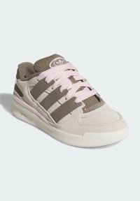 Beige suede sneaker with brown accents and mesh tongue. Features three brown stripes, pink laces, and textured white sole.