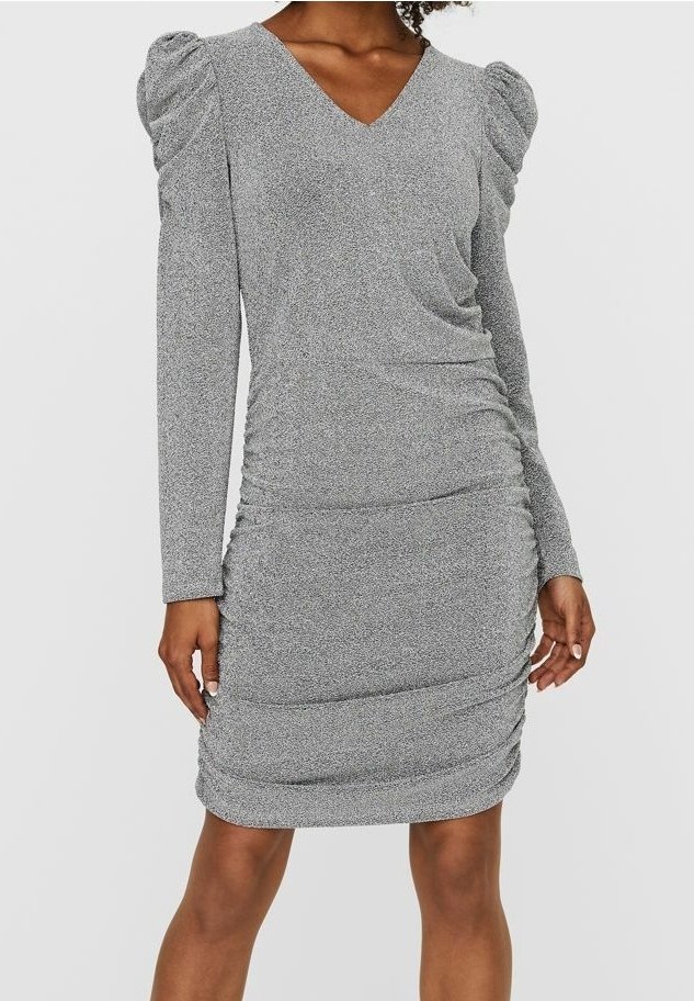Femme portant une mini-robe argentée-grise à manches longues froncées avec épaules bouffantes et un décolleté en V, debout devant un fond uni.