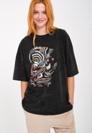Camiseta negra de gran tamaño con un acabado texturizado, que presenta un diseño gráfico colorido de animales y formas en el frente.