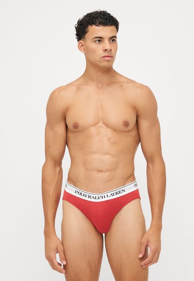 Rote Baumwoll-Unterhose mit einem weißen Bund, auf dem das Logo "POLO RALPH LAUREN" prangt. Enganliegendes Design betont die athletische Figur. Nahtloser Textur.