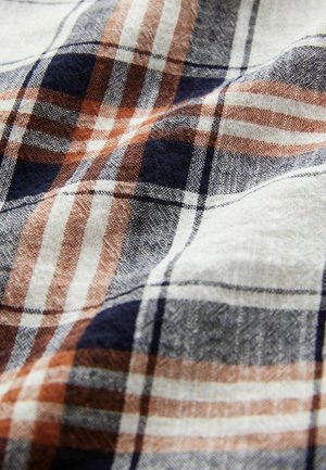 Tissu à carreaux avec des rayures beiges, bleu marine et couleur rouille. Tissage texturé avec une finition douce, présentant un motif à carreaux tissé.