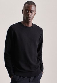Maglione nero a maglia con scollatura rotonda e maniche lunghe, caratterizzato da una finitura testurizzata e polsini e orlo a coste.
