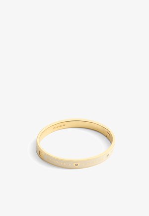 Gold-tone bangle bracelet featuring engraved "COACH" text and heart design, smooth finish, and a single small accent stone.