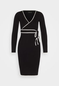 Robe noire côtelée à manches longues, col en V profond et bordure contrastante blanche. Dotée d'un design croisé et d'une ceinture nouée à la taille.