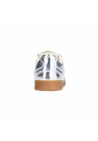 Metaalachtige zilveren sneaker met een gladde textuur, voorzien van een beige binnenkant, afgeronde vorm en een bruine rubberen zool.