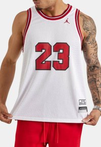 Hvid basketballtrøje med røde detaljer, der har et mesh-mønster, med nummeret "23" i fed skrift på fronten og et Jordan-logo på skulderen.