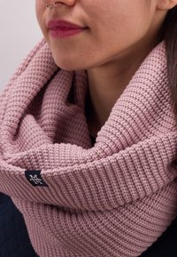 Knitted pink infinity scarf with a ribbed texture and soft material. Features a small navy label with a logo on the hem.