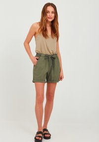 Light brown sleeveless top, olive green shorts with elastic waistband and tie, rolled cuffs, and black sandals. Simple design, casual look.