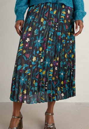 Gevouwen zwarte midi-rok met meerkleurige bloemprint, gedragen met een teal trui en metallic hoge hakken sandalen.
