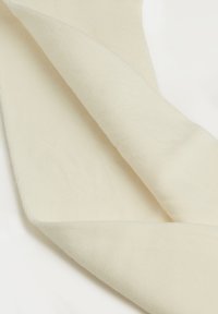 Cremfarbener Baumwollstoff mit gerippter Textur, gefaltet, um die Schichten und glatten Kanten zu zeigen. Leichte, weiche Oberfläche mit subtiler Schattierung.