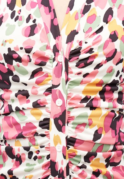 Prim-plan al unui material strâns cu un model floral abstract în roz, verde, galben, negru și alb, cu nasturi albi de-a lungul cusăturii centrale.