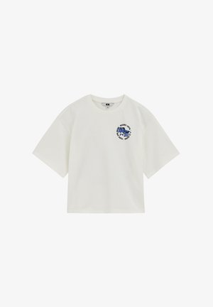 T-shirt blanc à manches courtes avec un petit graphisme bleu et un texte circulaire sur le côté gauche de la poitrine indiquant "Riviera Hotel à la Plage."