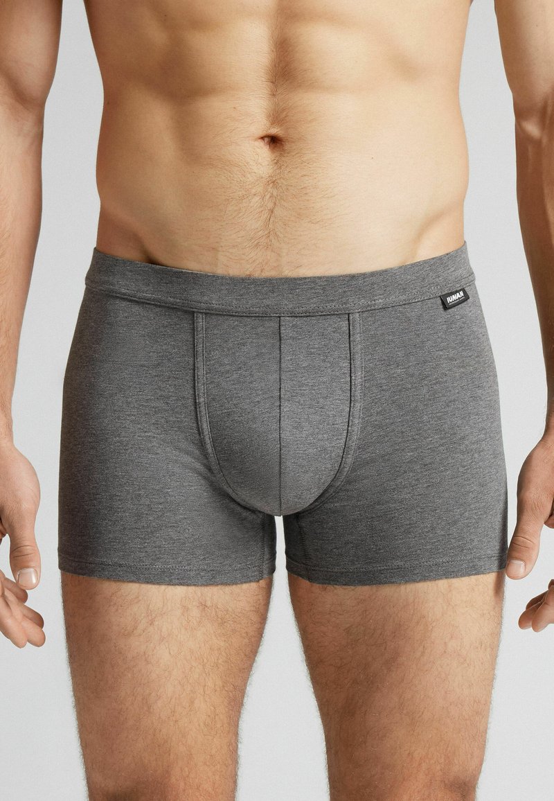 Boxers ajustados de algodón gris con costuras planas y abertura horizontal. Etiqueta visible en la cintura.