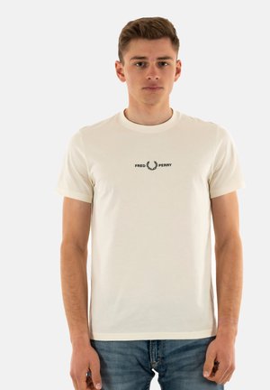 T-shirt di colore crema, a maniche corte, realizzata in morbido tessuto, con un piccolo logo nero con design di alloro sul petto. Vestibilità casual.