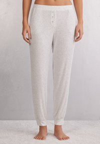 Lichtgrijze geribbelde pyjamabroek met een zachte textuur, voorzien van een knoopsluiting en elastische boorden bij de enkels, ontworpen voor comfort.