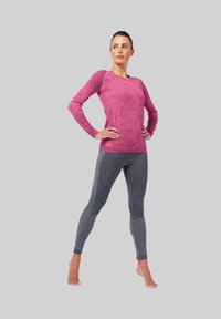 Roze lange mouwen sporttop met een gestructureerd patroon, gecombineerd met donkergrijze leggings met subtiele strepen en een aansluitend ontwerp.