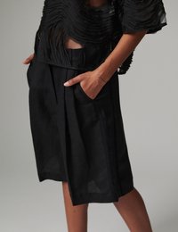 Μαύρα λινά σορτς με άνετη εφαρμογή, μήκος μέχρι το γόνατο και εμπρόσθιες τσέπες. Το ύφασμα έχει διακριτική υφή και ελαφριά όψη.